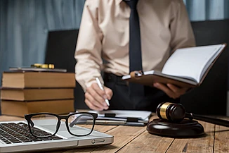 portatil con gafas y mazo con abogado desenfocado de fondo